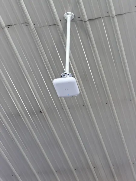 UniFi access point mounted from the ceiling of a pole barn
